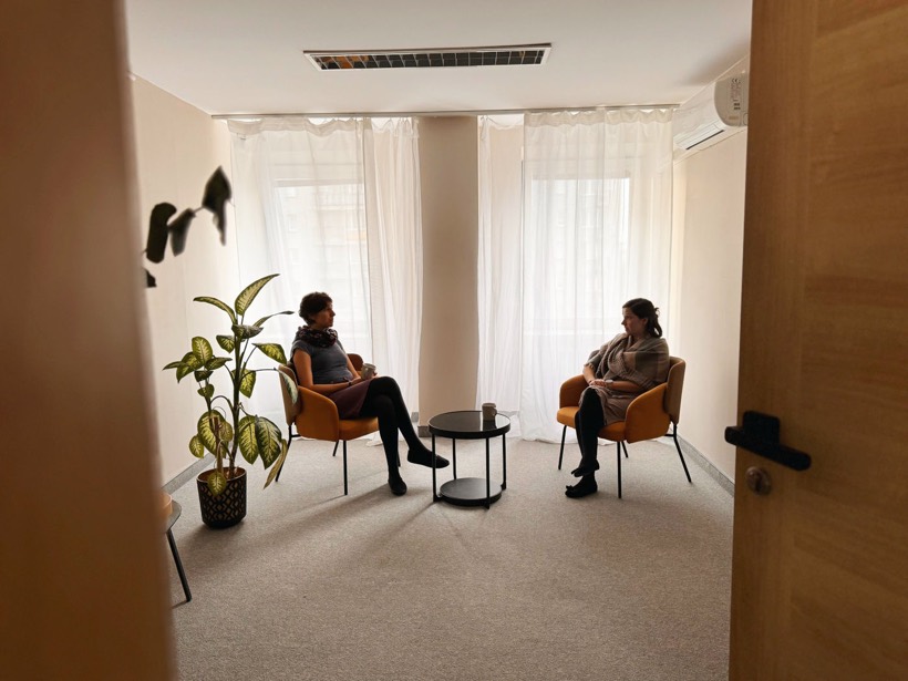 Rozmowa w gabinecie poradni - dwa fotele przy oknie z firaną i roślina
